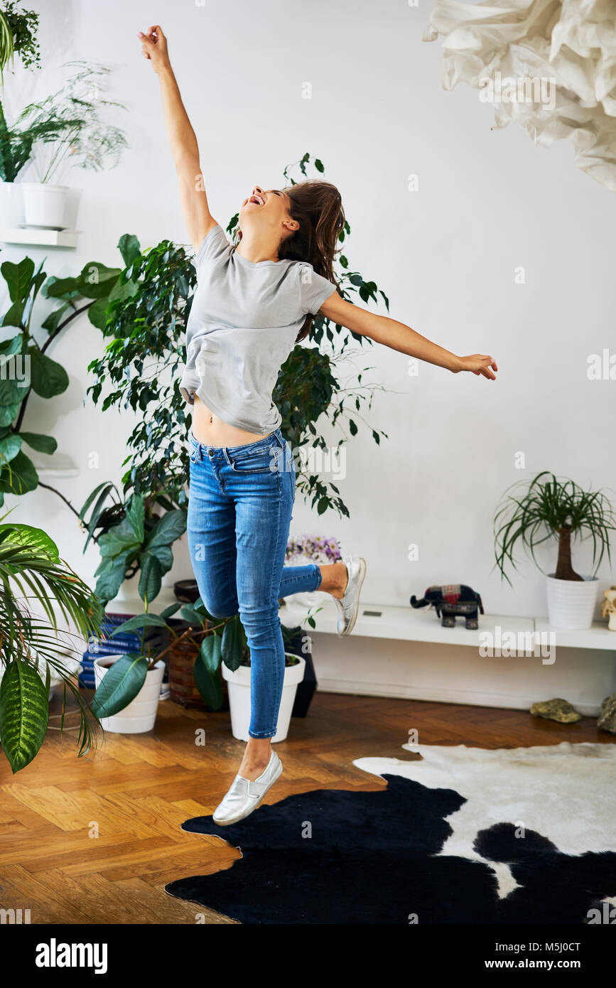 Ausgelassene junge Frau in einem Zimmer springen Stockfoto