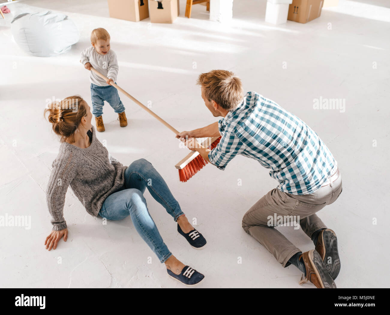 Vater und Tochter Spaß mit einem Besen in einem Loft Stockfoto