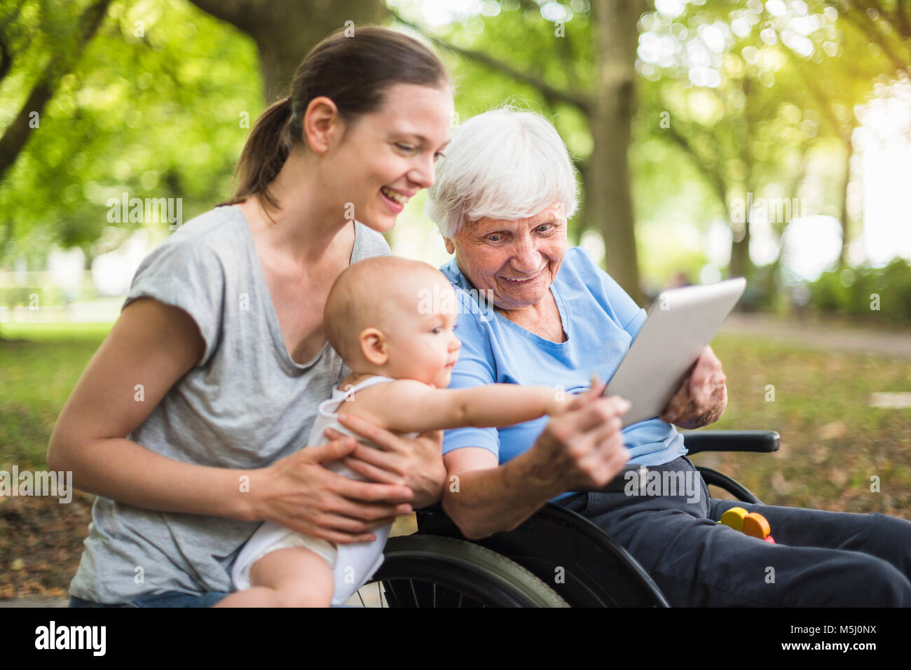 Großmutter, Tochter und Enkelin Spaß mit Tablet-PC in einem Park Stockfoto