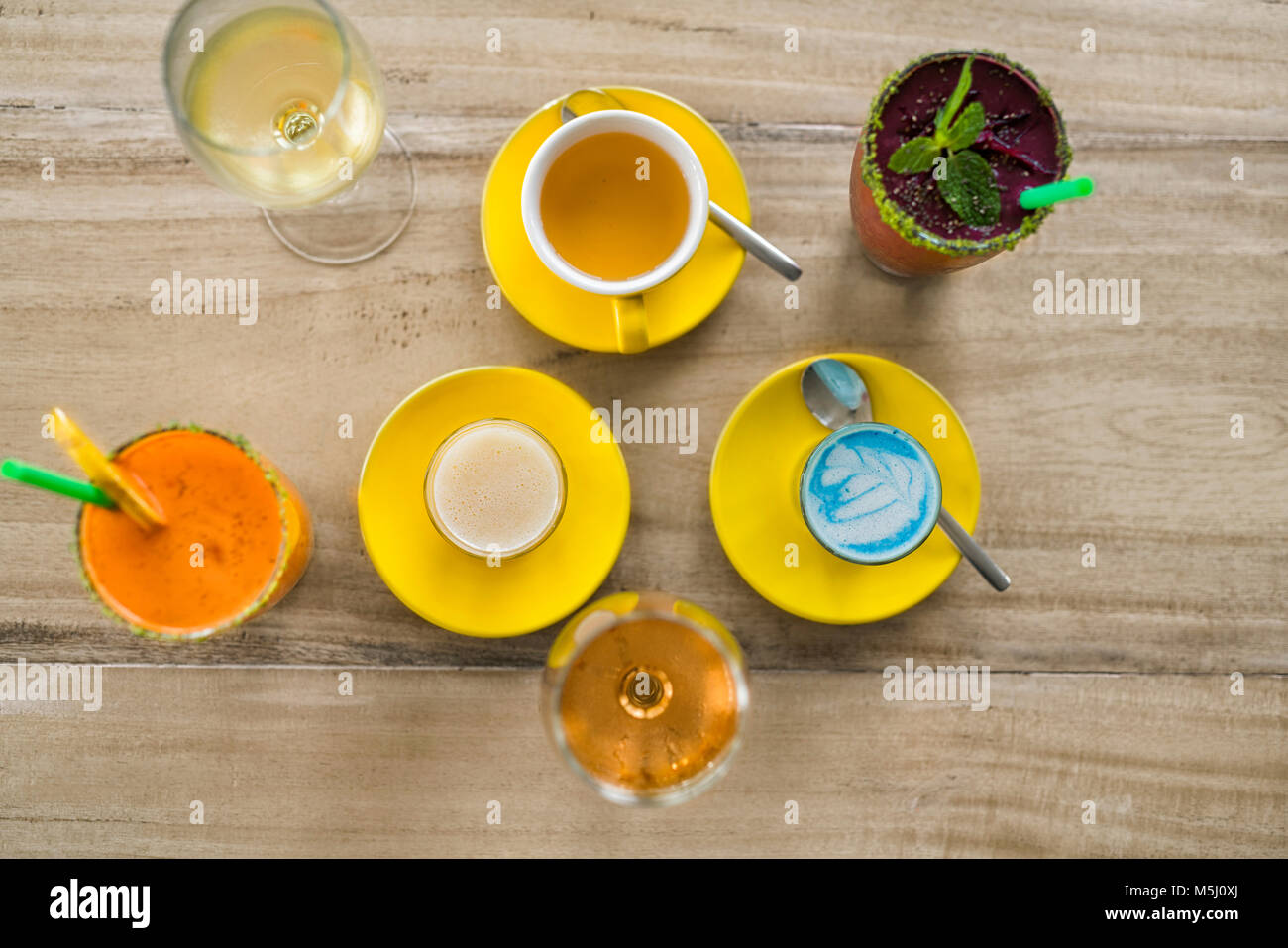 Holztisch mit verschiedenen Getränken wie smurf Latte, Smoothie, Wein und Kaffee Stockfoto