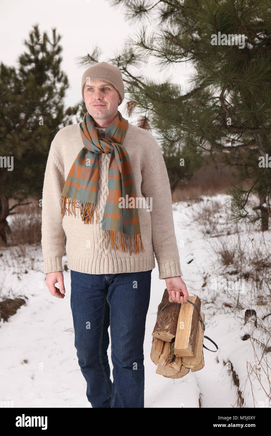 Reifer Mann mit einem Bündel von Brennholz in einem Winter Forest Stockfoto