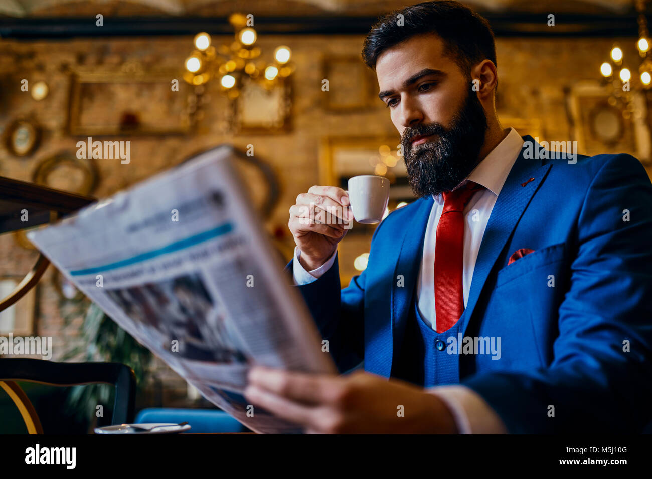 Eleganten mann Kaffee trinken und lesen Zeitung in einem Cafe Stockfoto