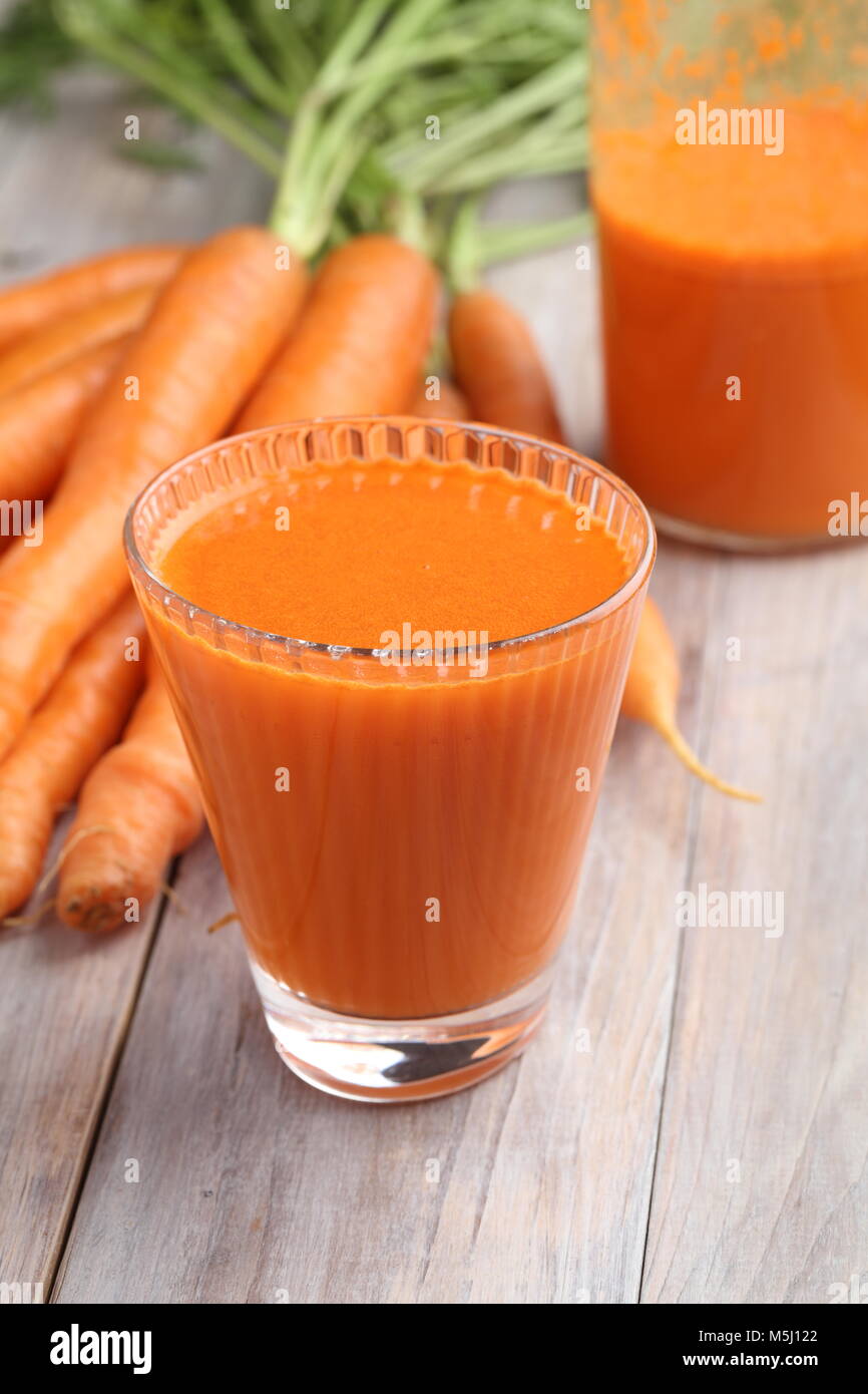 Tasse Karottensaft und frisches Gemüse auf einem rustikalen Tisch Stockfoto