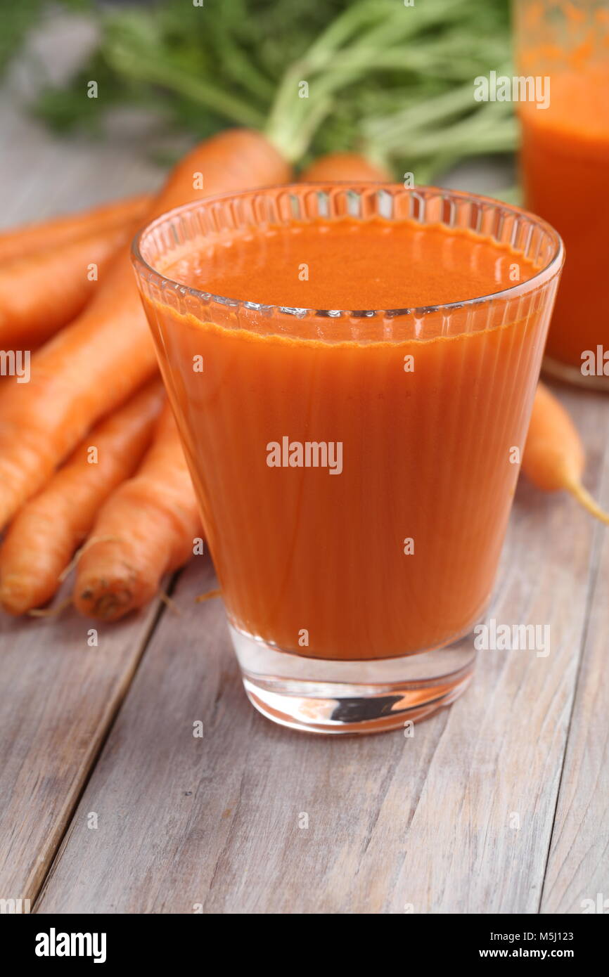 Tasse Karottensaft und frisches Gemüse auf einem rustikalen Tisch Stockfoto
