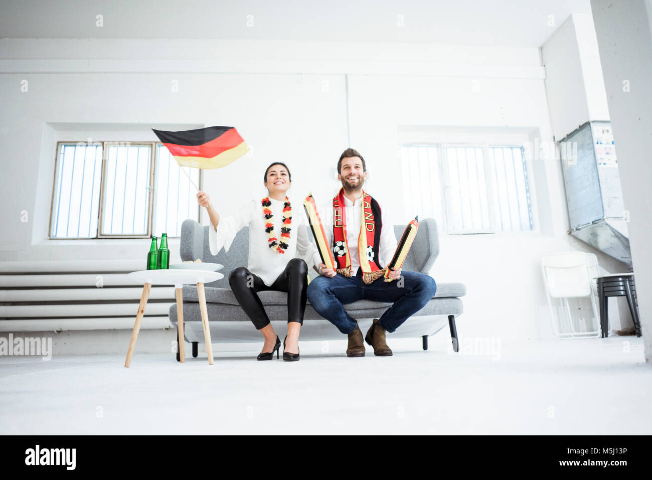 Happy German football fan Paar sitzt auf der Couch vor dem Fernseher Stockfoto