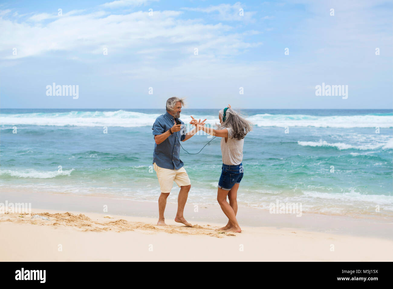 Schönes älteres Ehepaar mit Kopfhörer tanzen am Strand Stockfoto