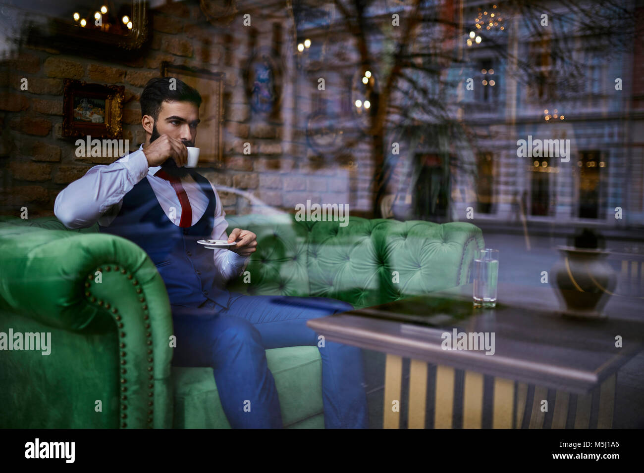 Modische junge Mann sitzt am Tisch in einem Cafe Kaffee trinken Stockfoto