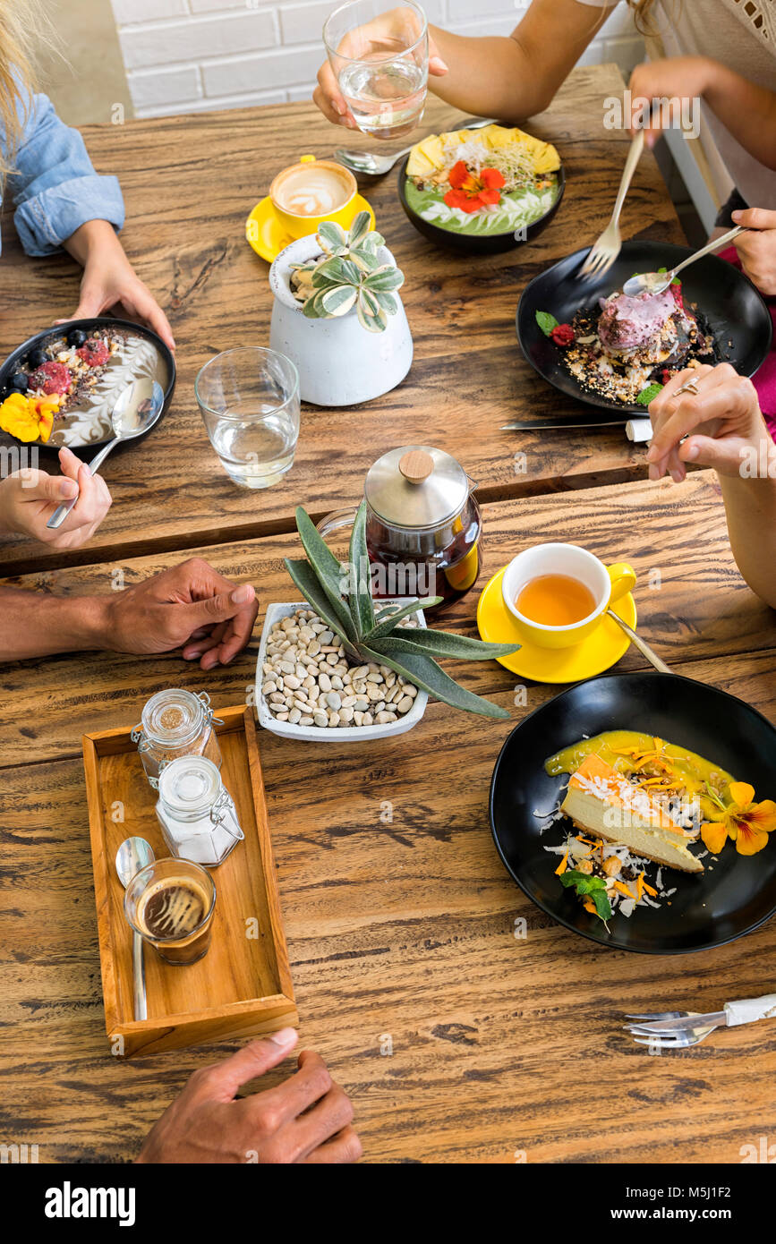 Menschen, die sich um hölzernen Tisch essen und trinken verschiedene Lebensmittel Stockfoto
