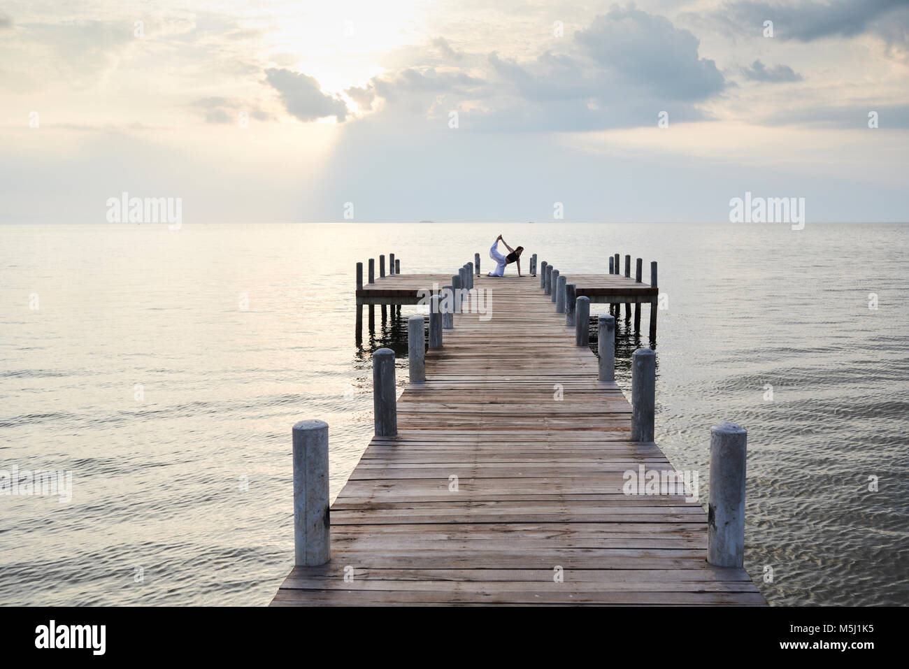 Yoga Lehrer in Bird Dog Position gegen den Sonnenuntergang und das Meer. Kep, Kambodscha. Stockfoto