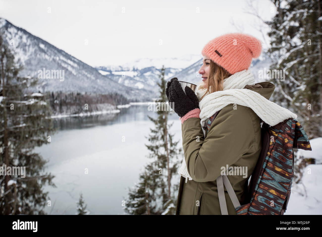 Junge Frau mit heißen Getränk in der alpine Winter Landschaft mit See Stockfoto