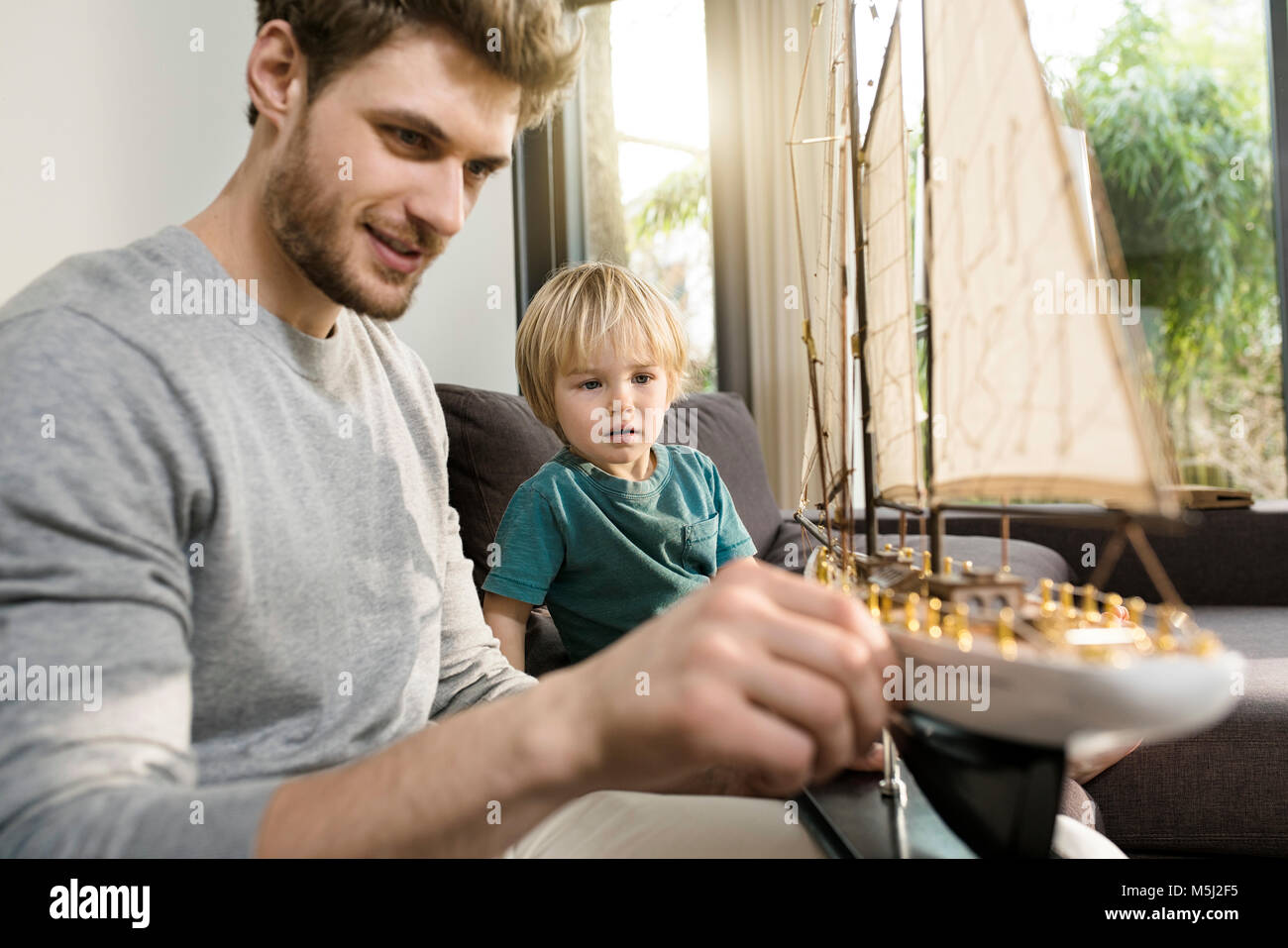 Vater und Sohn im Toy model ship auf der Couch zu Hause suchen Stockfoto