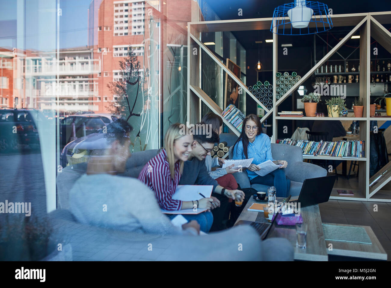 Eine Gruppe von Freunden zusammen sitzen in einem Cafe mit Reflexion der Glasscheibe Stockfoto