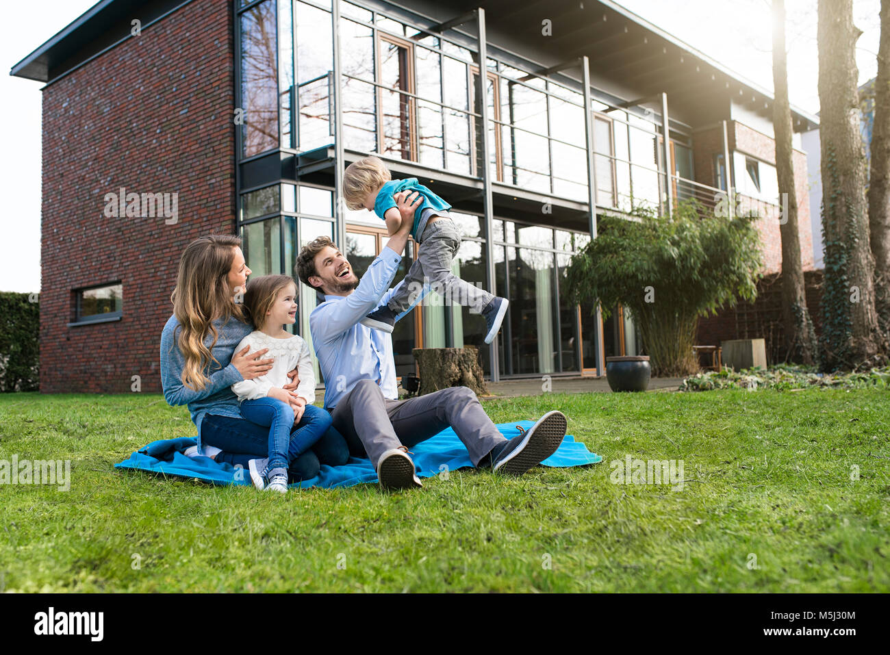 Happy Family auf die Decke im Garten vor ihrem Haus mit Vater, Sohn litfting Stockfoto