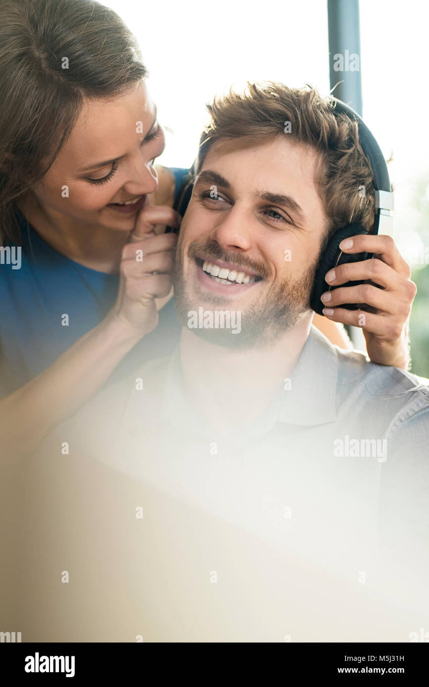 Lächelnde Frau mit Kopfhörer auf Freund Stockfoto