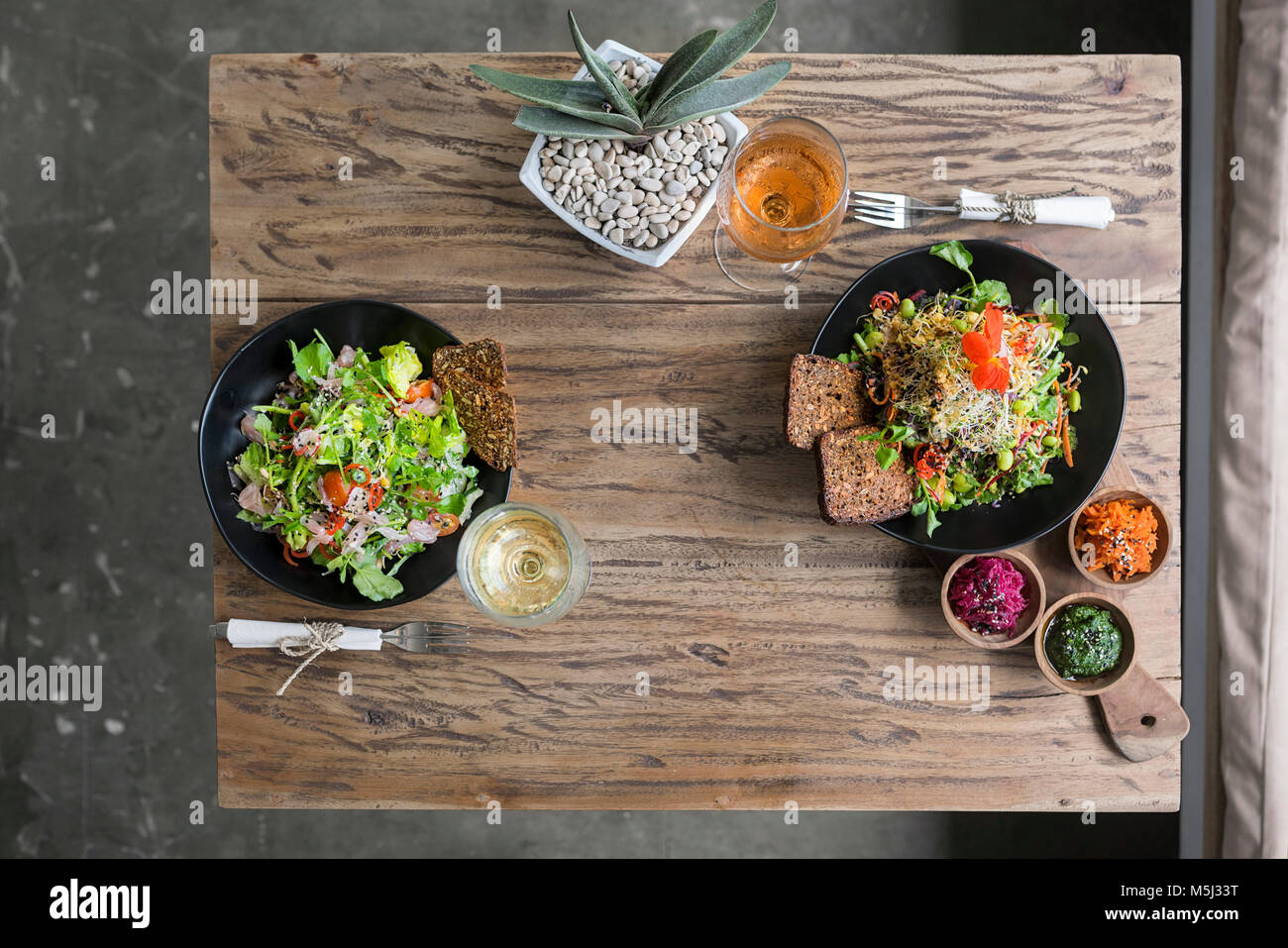 Dekoriert salat Schüsseln auf hölzernen Tisch mit Gläsern Wein Stockfoto