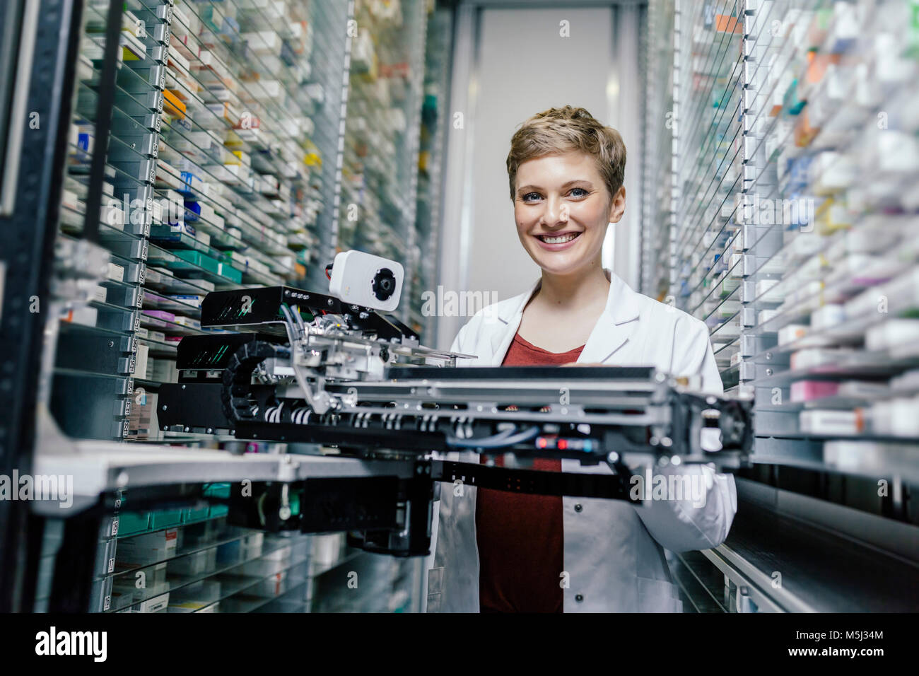Lächelnd Apotheker mit der Inbetriebnahme der Maschine in der Pharmazie Stockfoto