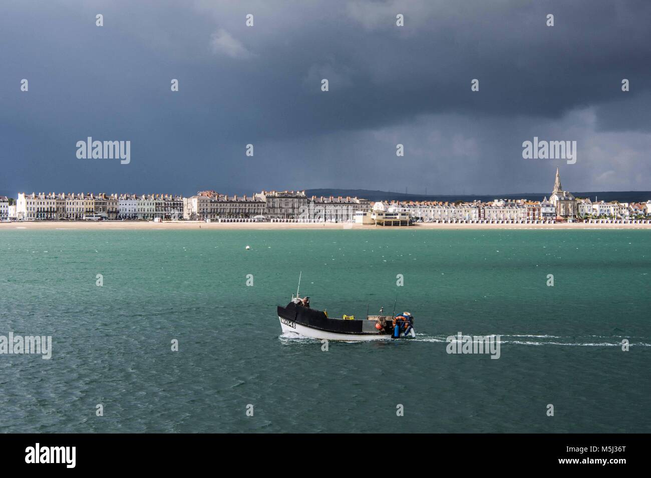 Weymouth Bay und fahrenden Boot an einem stürmischen Tag. Wie von der steinernen Pier gesehen. Stockfoto