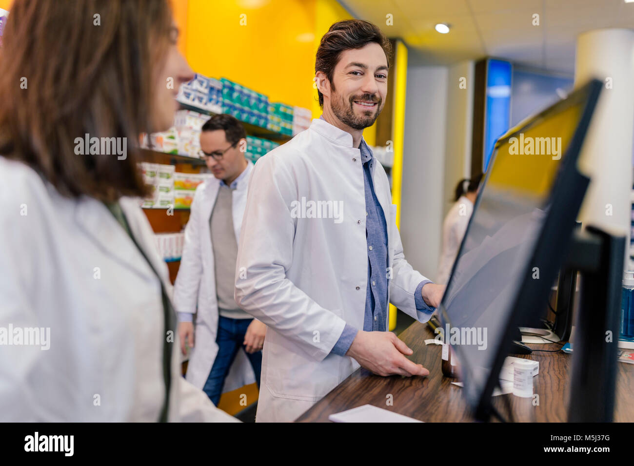 Portrait von lächelnden Apotheker mit Kollegen am Zähler in der Pharmazie Stockfoto