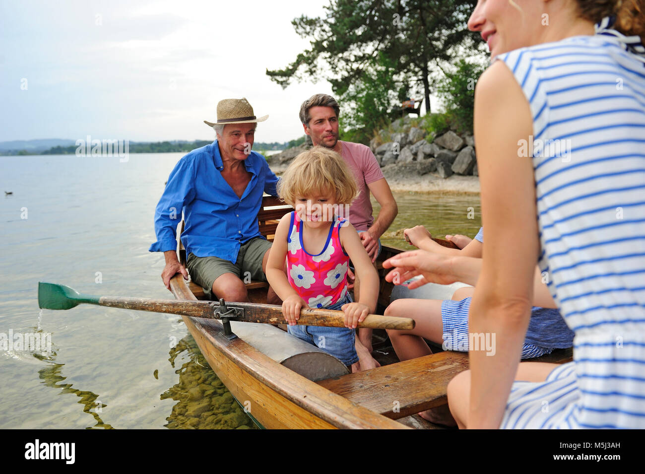Deutschland, Bayern, Murnau, glückliche kleine Mädchen mit ihrer Familie im Ruderboot am Seeufer Stockfoto