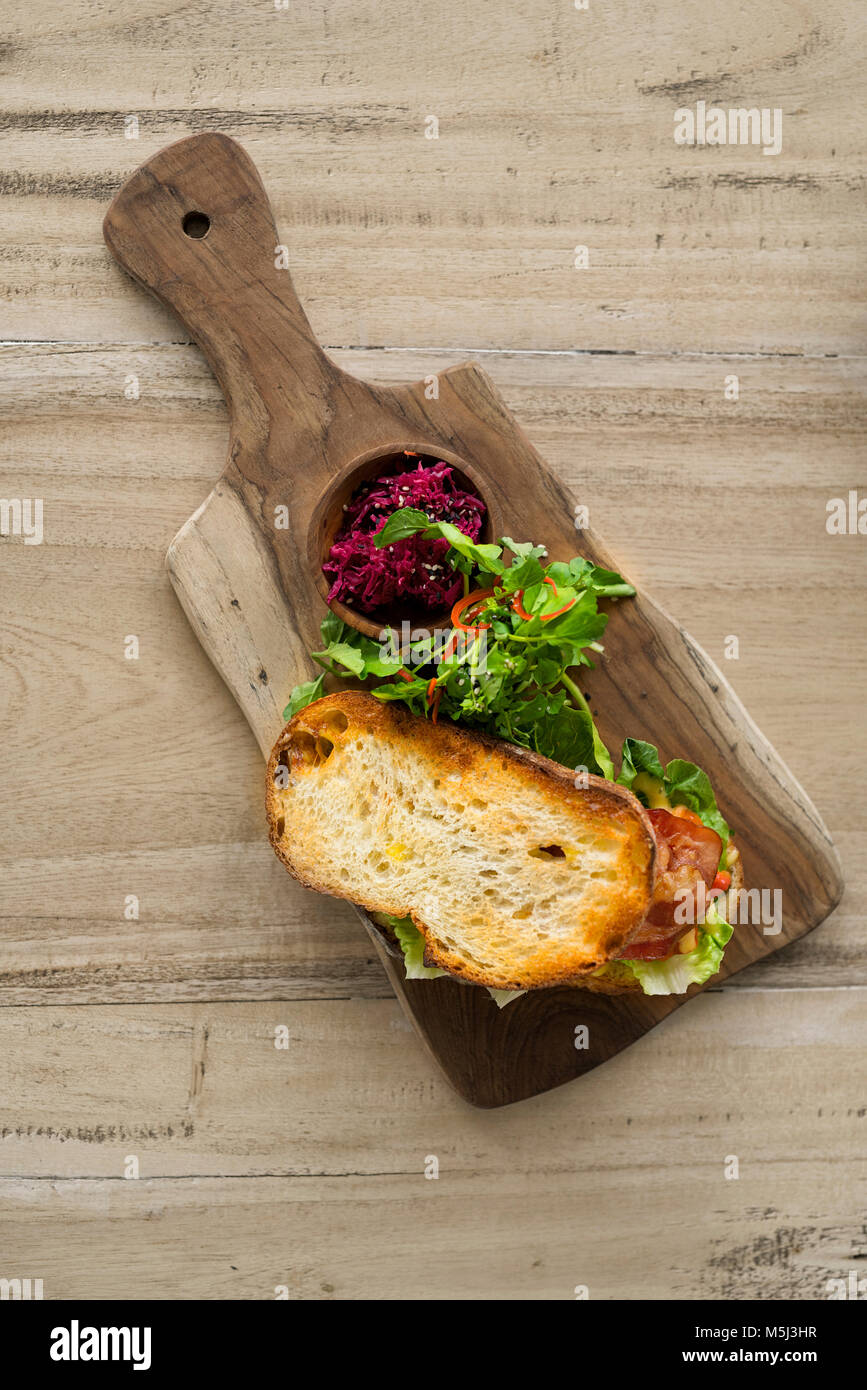 Knuspriges Brot mit grünem Salat und Schinken auf Holzplatte Stockfoto