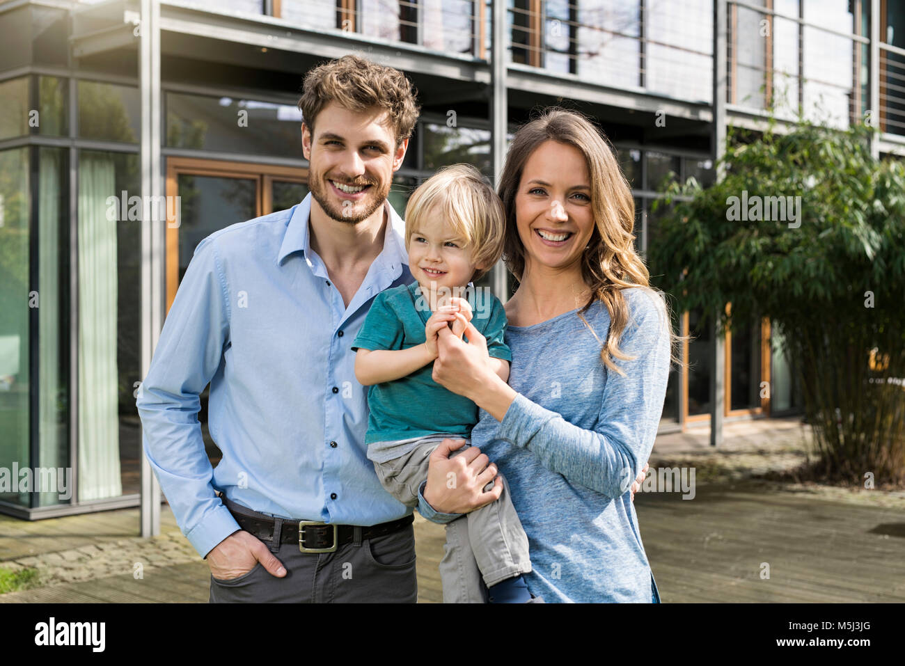 Portrait von lächelnden Eltern mit Sohn vor ihrem Haus Stockfoto