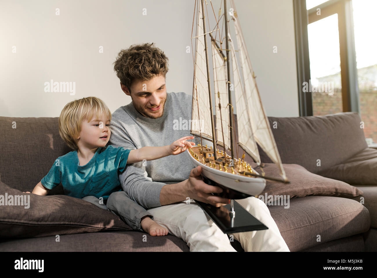 Vater und Sohn im Toy model ship auf der Couch zu Hause suchen Stockfoto