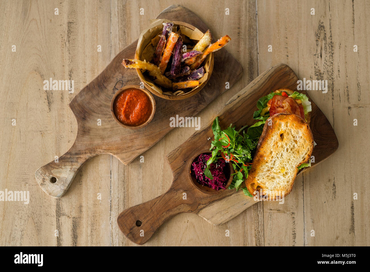 Zwei Holz- platten mit hausgemachten süßen Kartoffeln und Pommes Frites, Tomaten-dip und knuspriges Brot mit Salat, Schinken und Rote Bete Stockfoto
