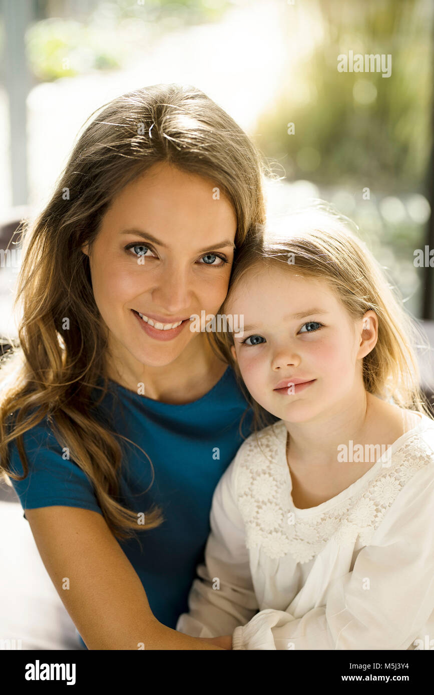 Portrait von lächelnden Mutter mit Tochter vor Fenster Stockfoto