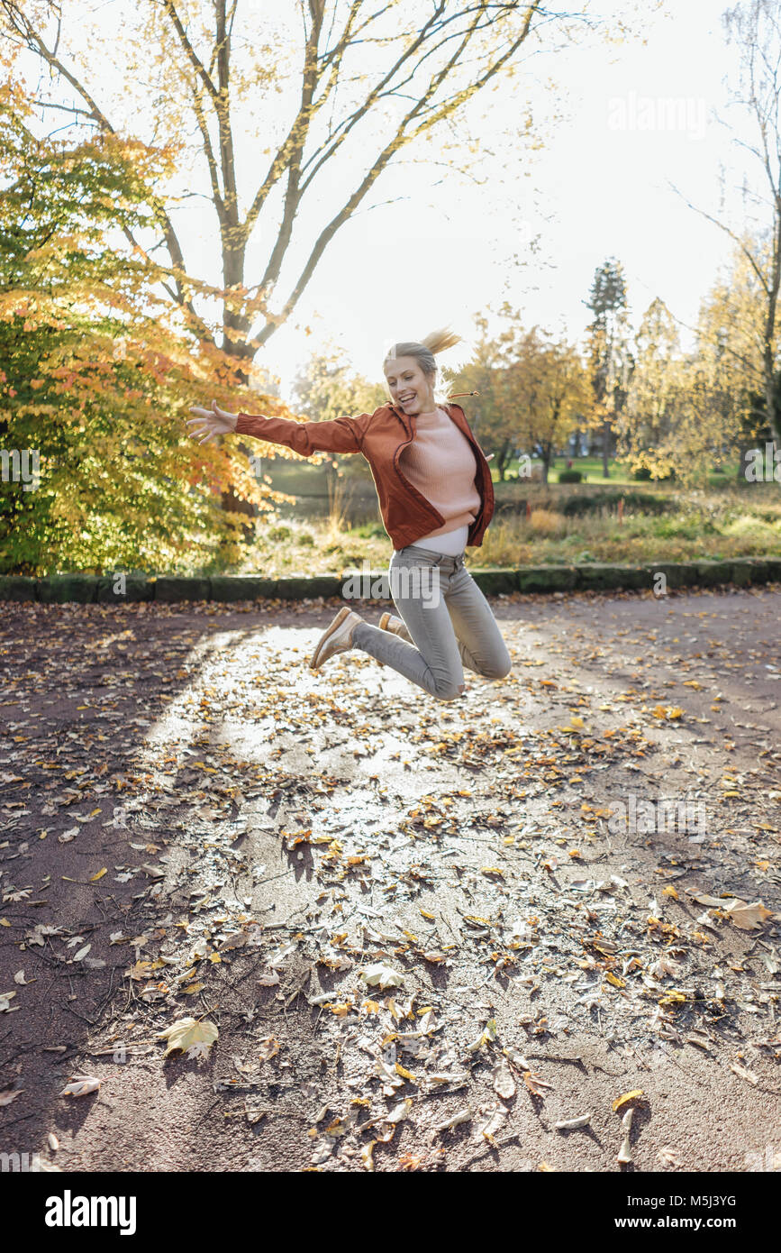 Glückliche junge Frau, springen in die Luft, im herbstlichen Park Stockfoto