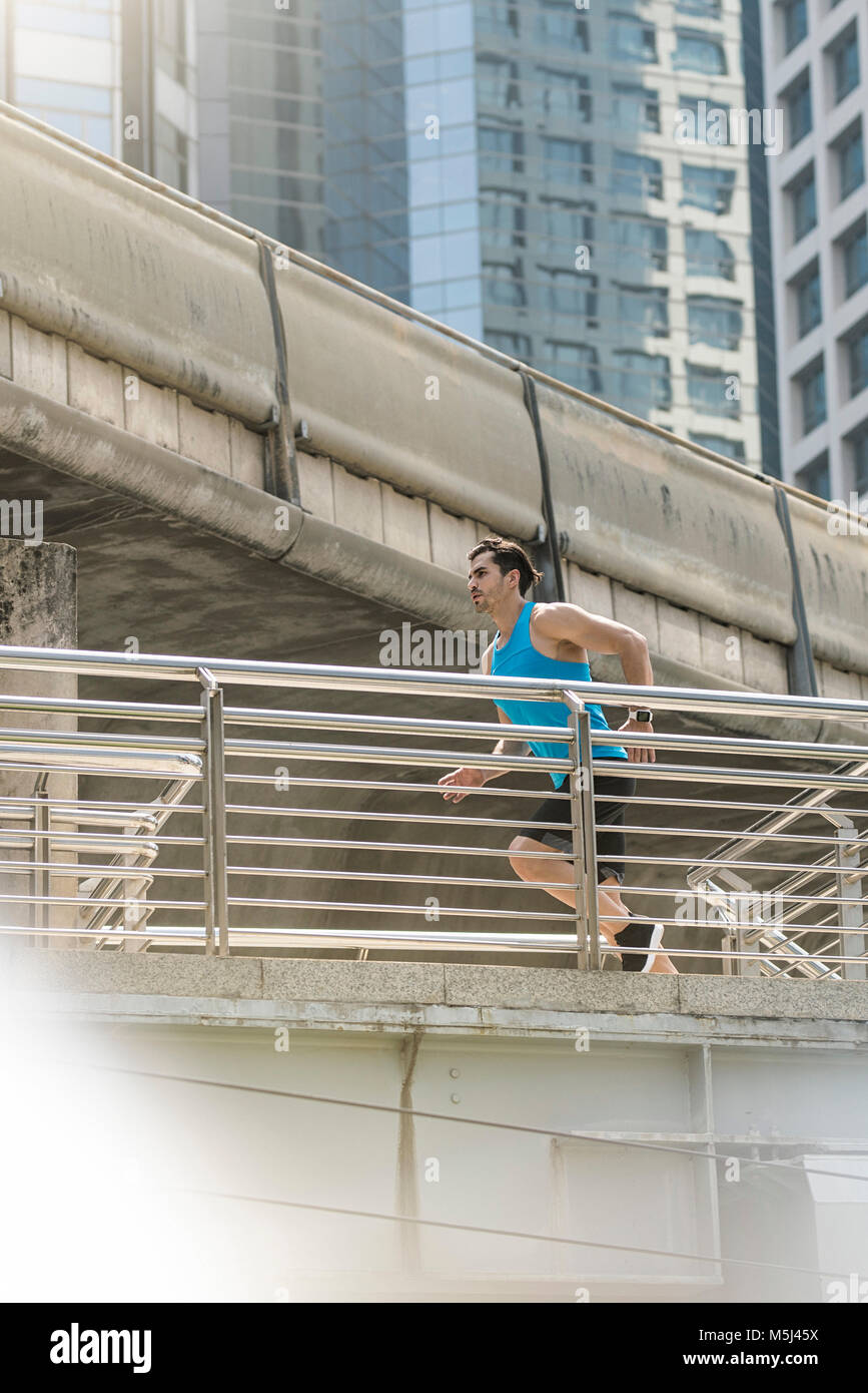 Läufer in Blue Fitness shirt über moderne Brücke läuft Stockfoto