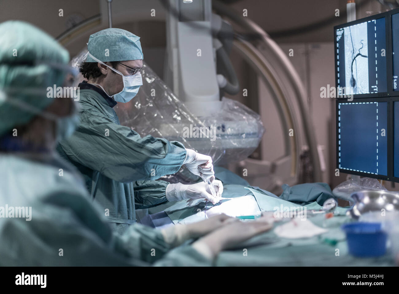 Neuroradiologist mit Assistant mit der Spritze während einer Operation Stockfoto