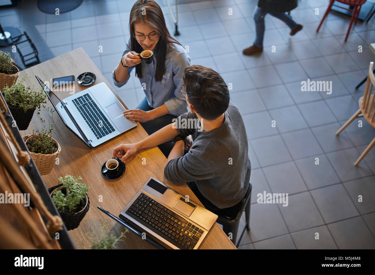 Junge Frau und Mann in einem Cafe mit eigenem Laptop sprechen und trinken espresso Stockfoto
