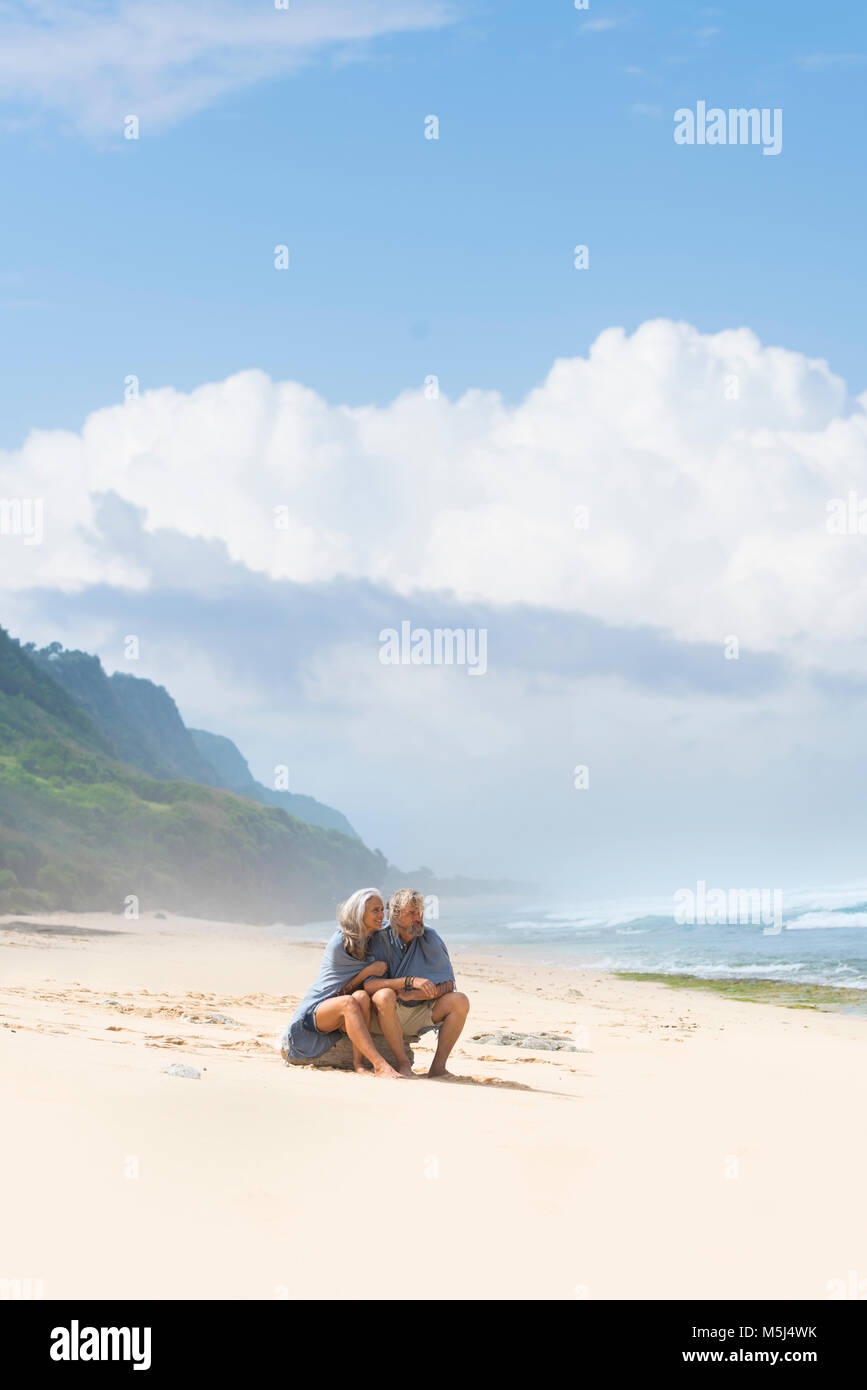 Senior Paar am Strand zu sitzen, in eine Decke gewickelt Stockfoto