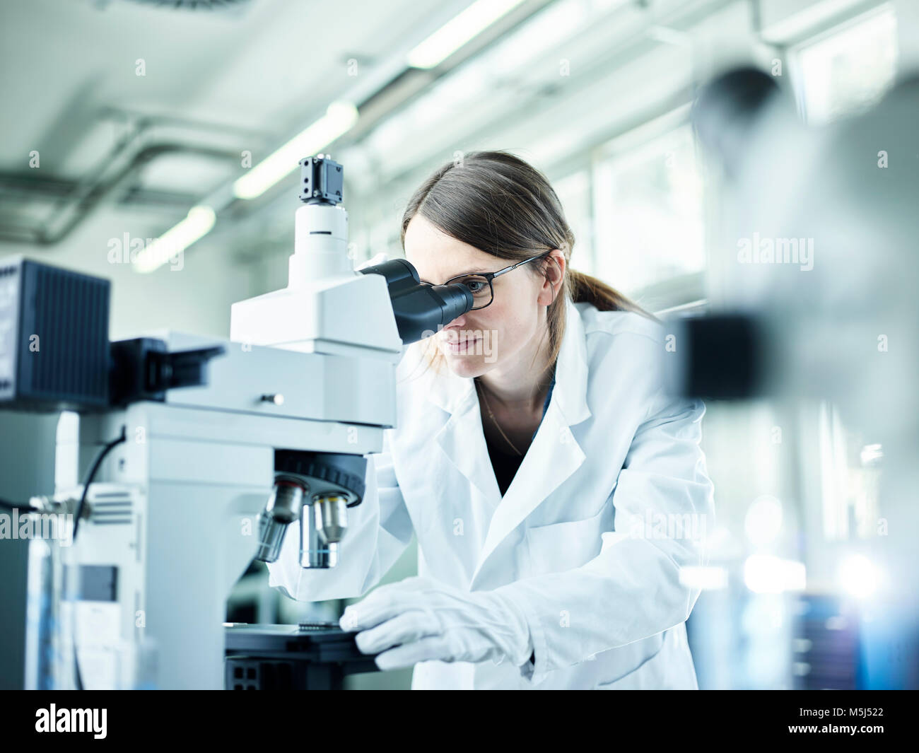 Labortechniker durch Mikroskop im Labor Stockfoto
