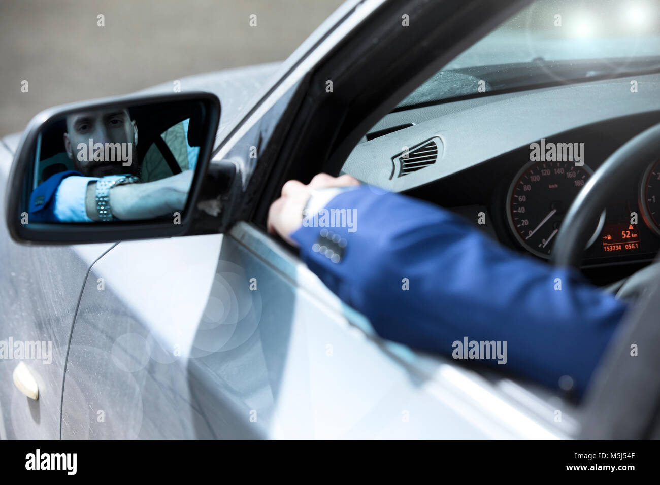 Junger Mann mit seinem Auto fährt, im Rückspiegel auf der Suche Stockfoto