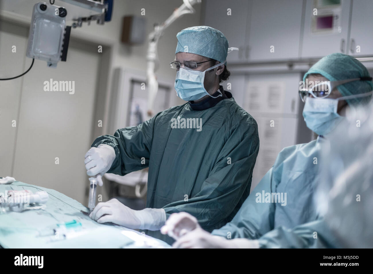 Neuroradiologist mit Assistant mit der Spritze während einer Operation Stockfoto