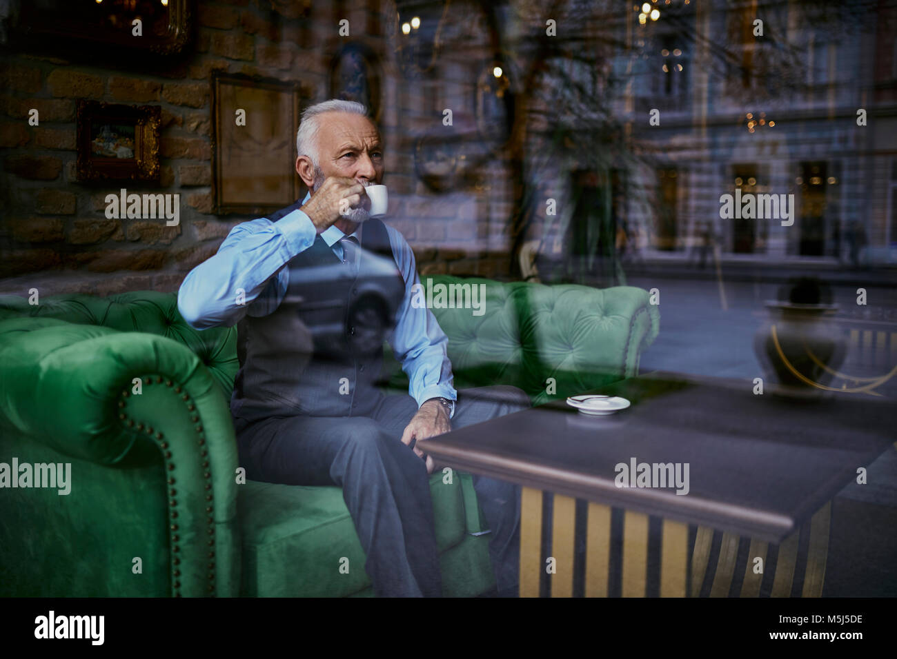 Elegante älterer Mann sitzt am Tisch in einem Cafe Kaffee trinken Stockfoto