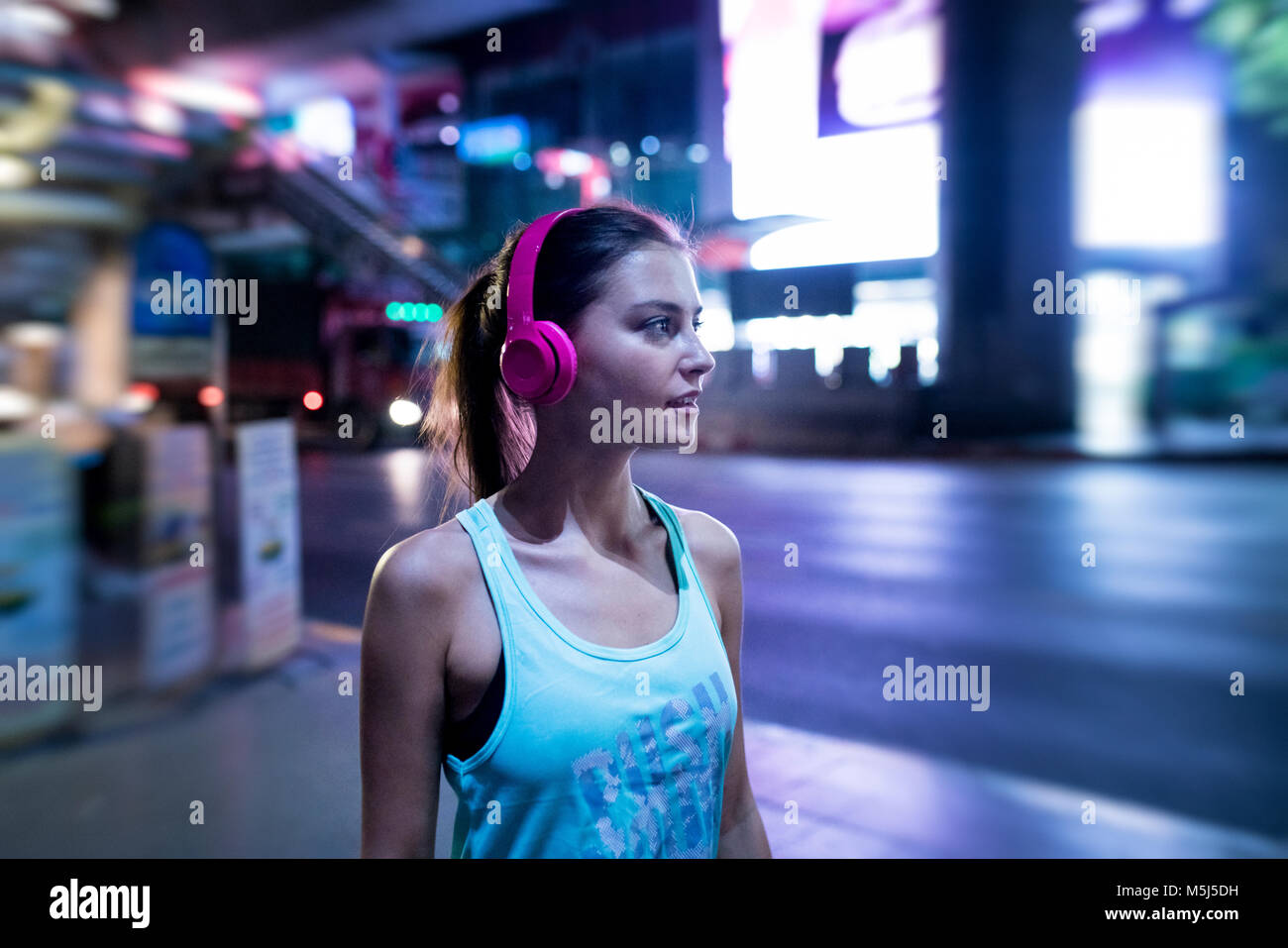 Junge Frau in Rosa sportshirt in der modernen urbanen Umgebung bei Nacht Stockfoto