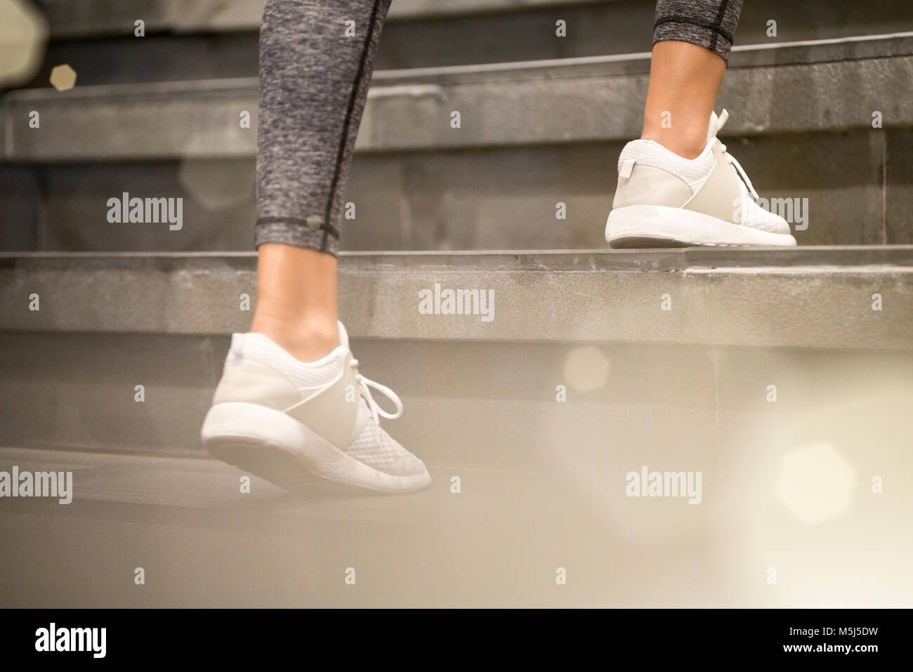 In der Nähe der weiblichen Beine mit weißen Sport Turnschuhe läuft die Treppe Stockfoto