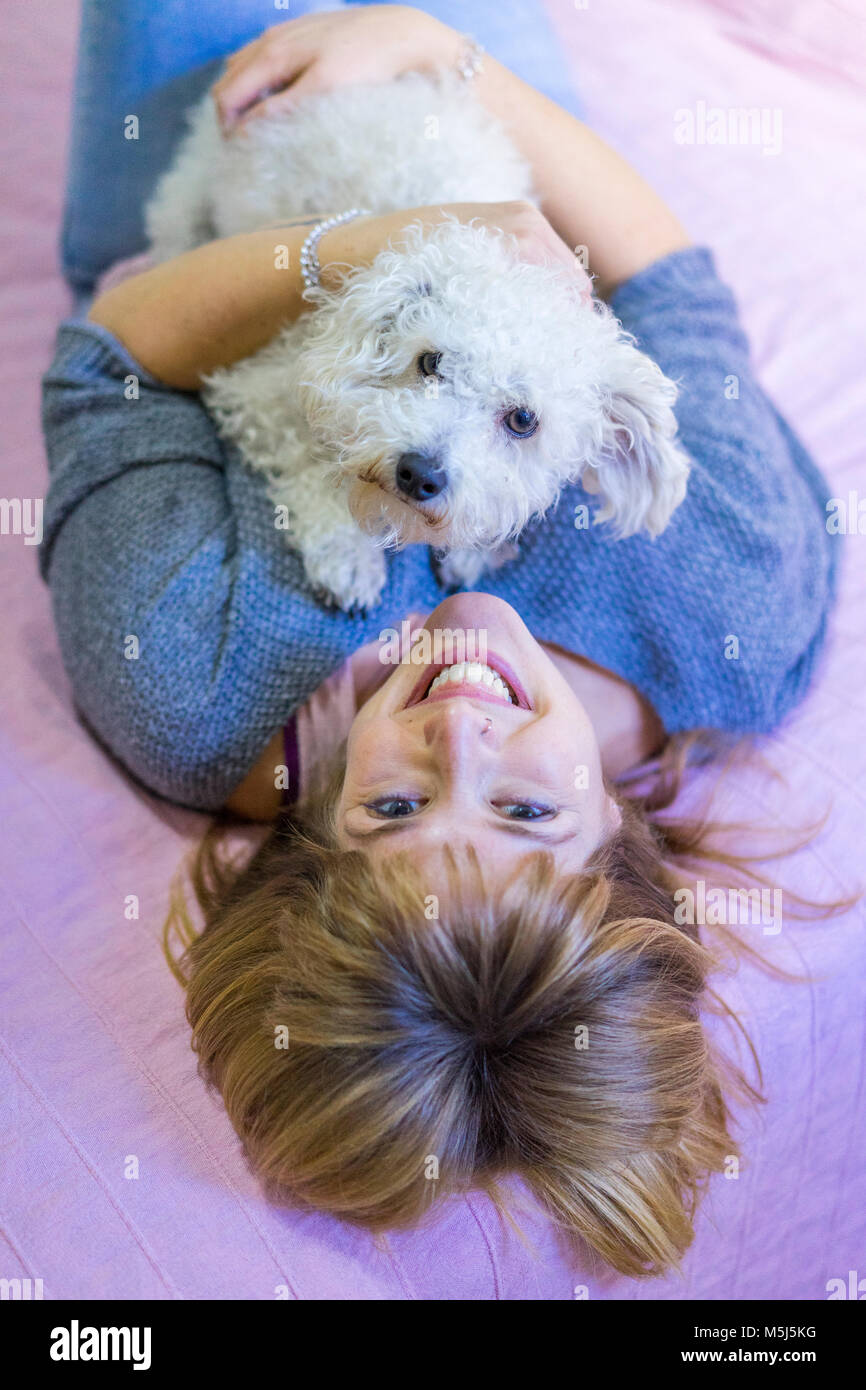 Portrait von Frau liegend auf Bett mit ihrem Hund Stockfoto