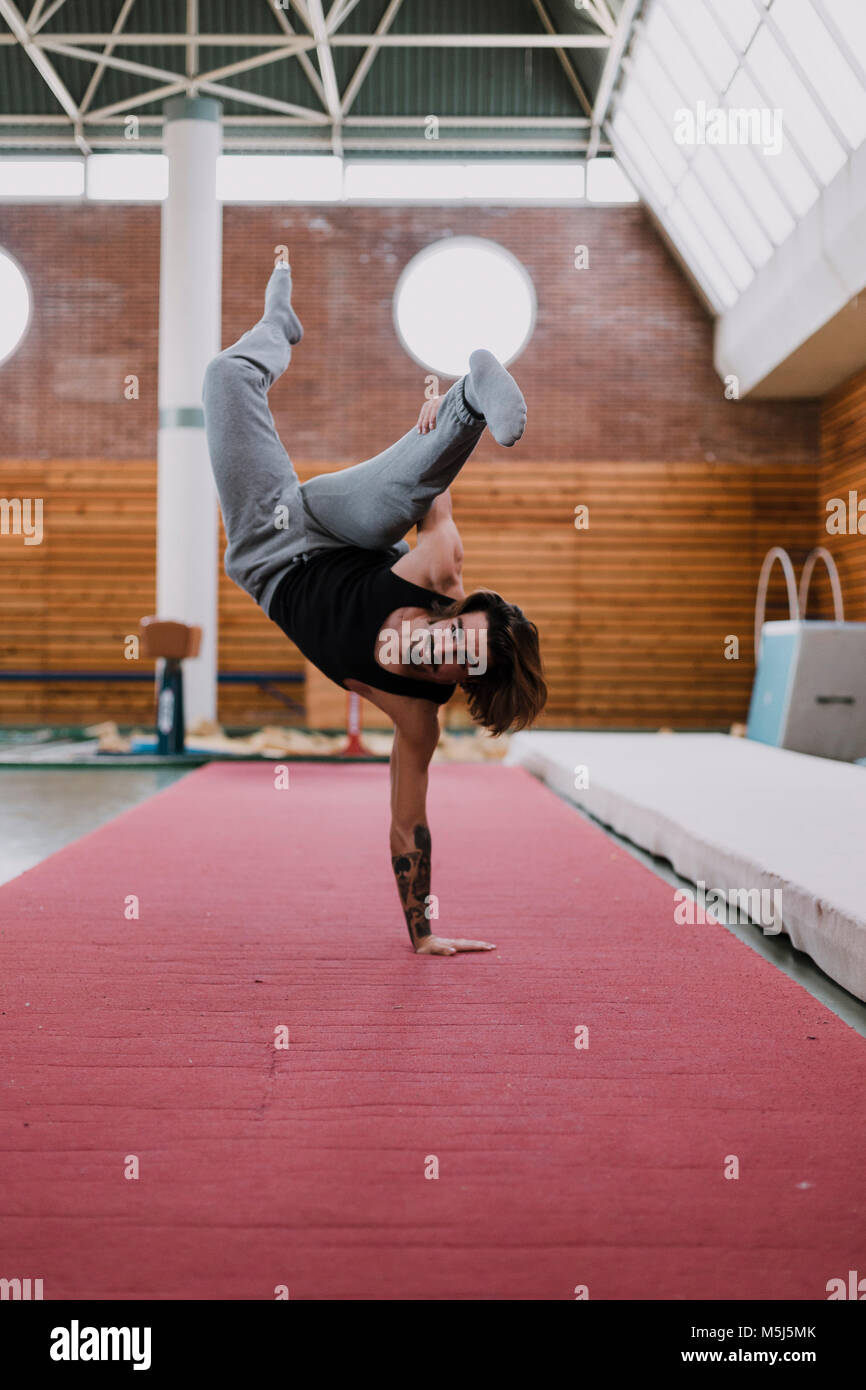 Junger Mann dabei akrobatische Übung in der Turnhalle Stockfoto