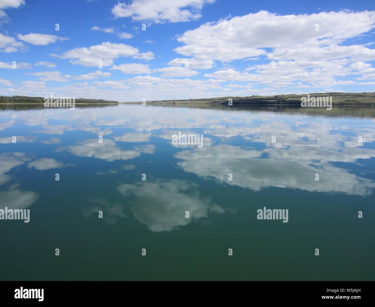 Eine große Gruppe von puffy Wolken schweben in der Luft, und reflektiert auf den ruhigen friedlichen See unterhalb Stockfoto