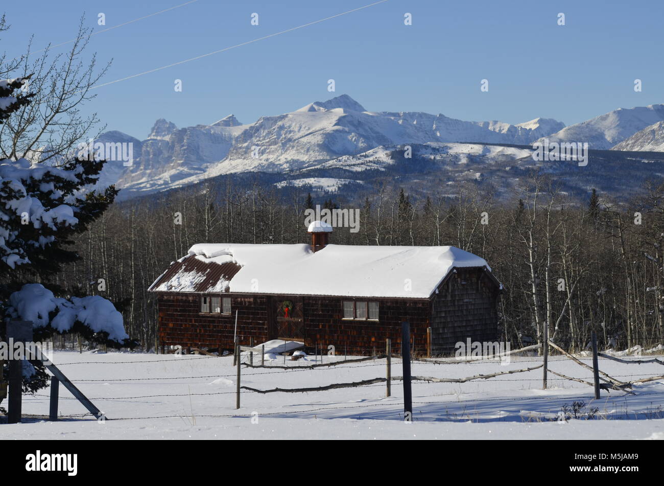 Eine alte historische Hütte, mit einem herrlichen Schnee auf die Berge in der Ferne Stockfoto