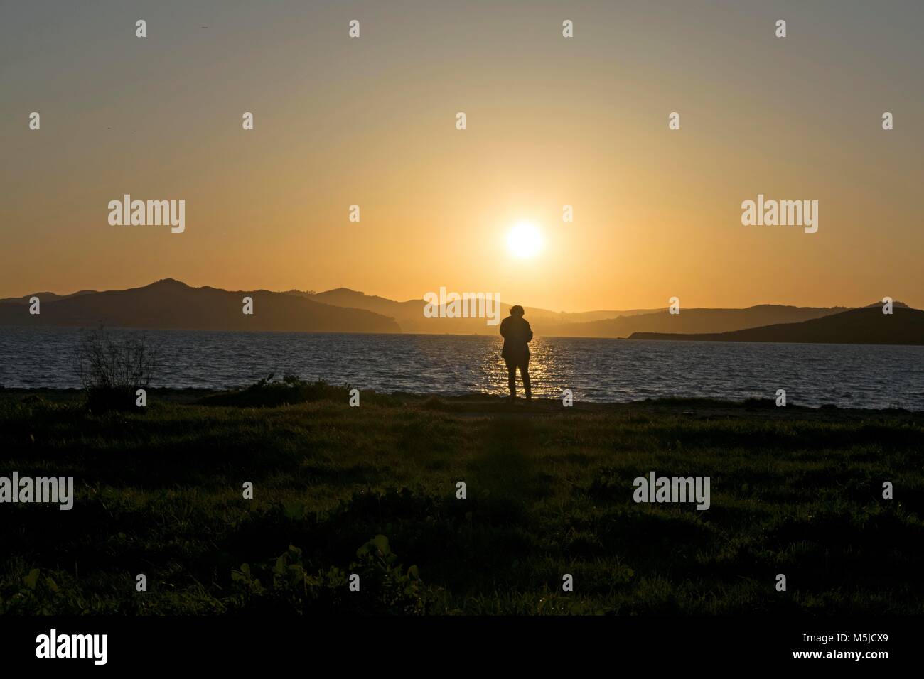 Eine Frau sieht den Sonnenuntergang in der Nähe von Oakland, CA Stockfoto