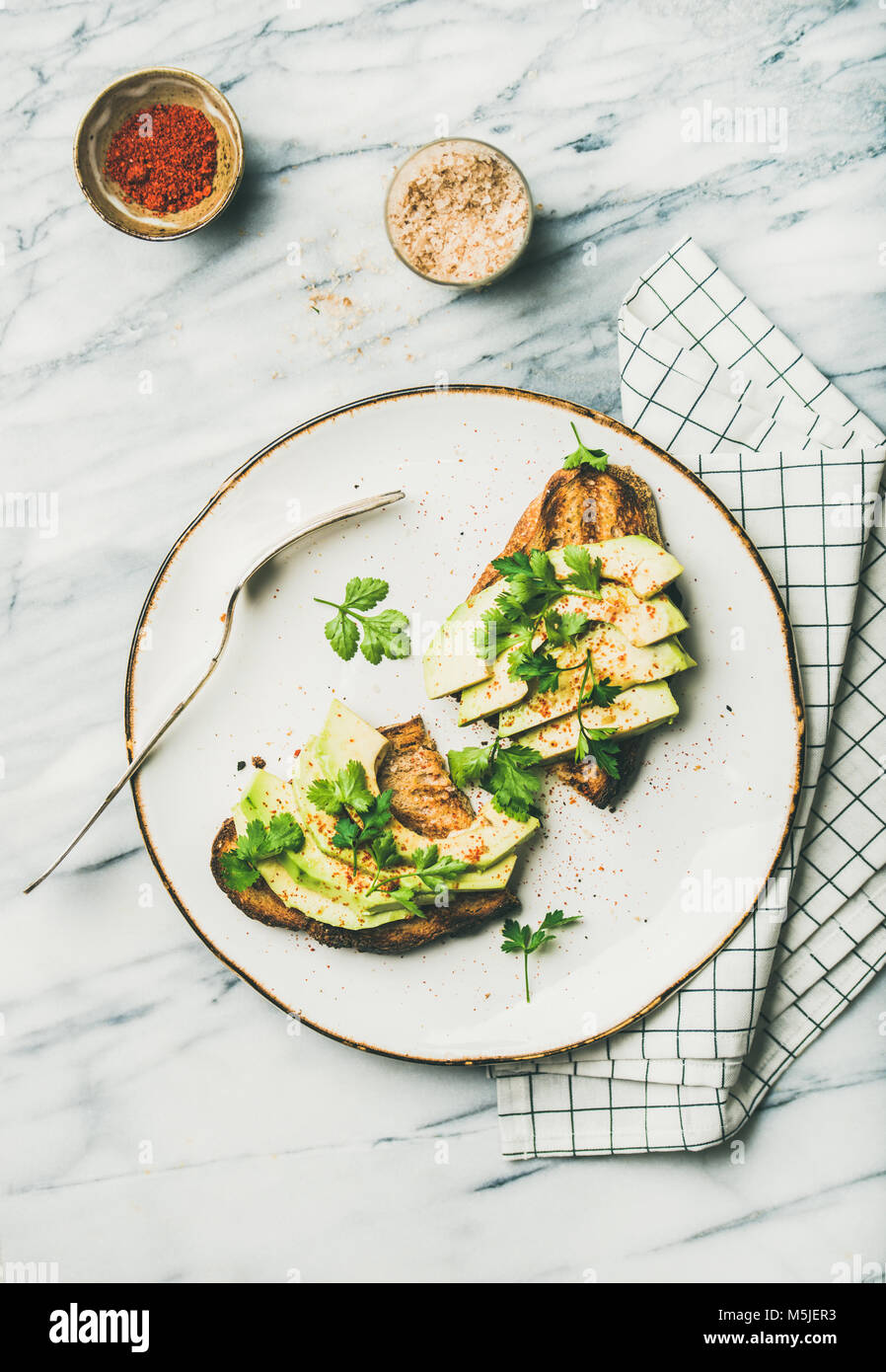 Flachbild-lay von Avocado Toast mit Gewürz Stockfoto