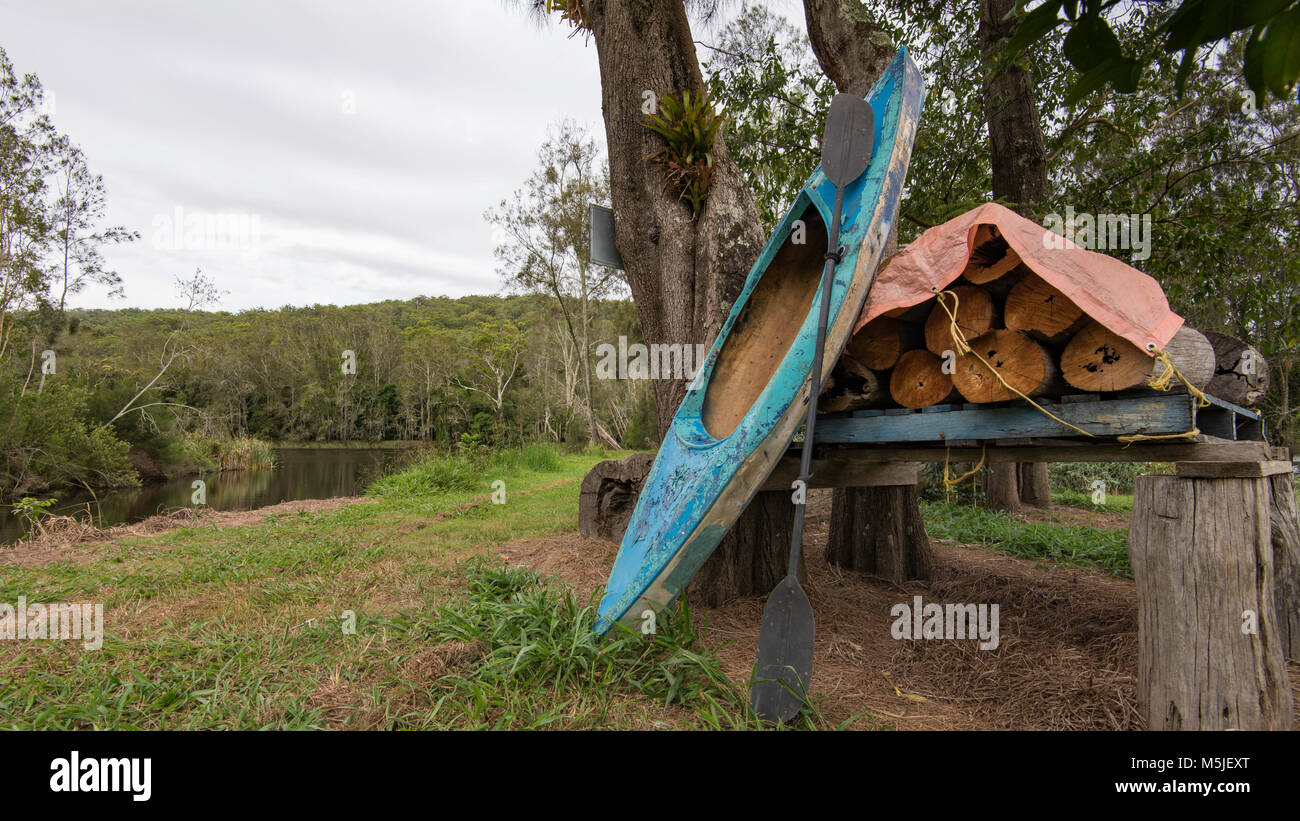 Ein Kajak und gestapelten Brennholz auf einem Grundstück neben Warrell Creek, dass die Nambucca River an der Nordküste von New South Wales, Australien verbindet Stockfoto