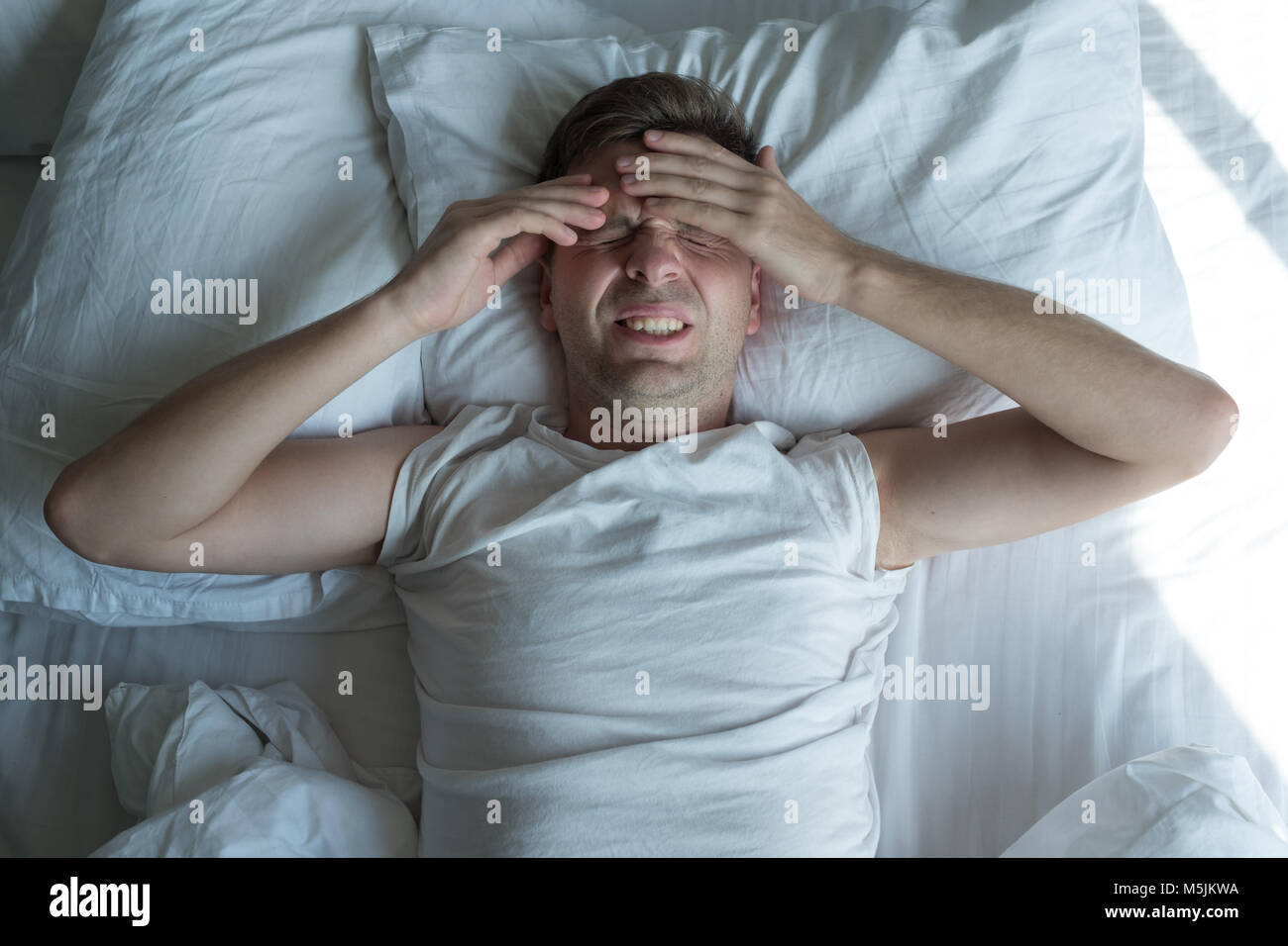 Mann im Bett liegen zu Hause leiden unter Kopfschmerzen oder Kater Stockfoto