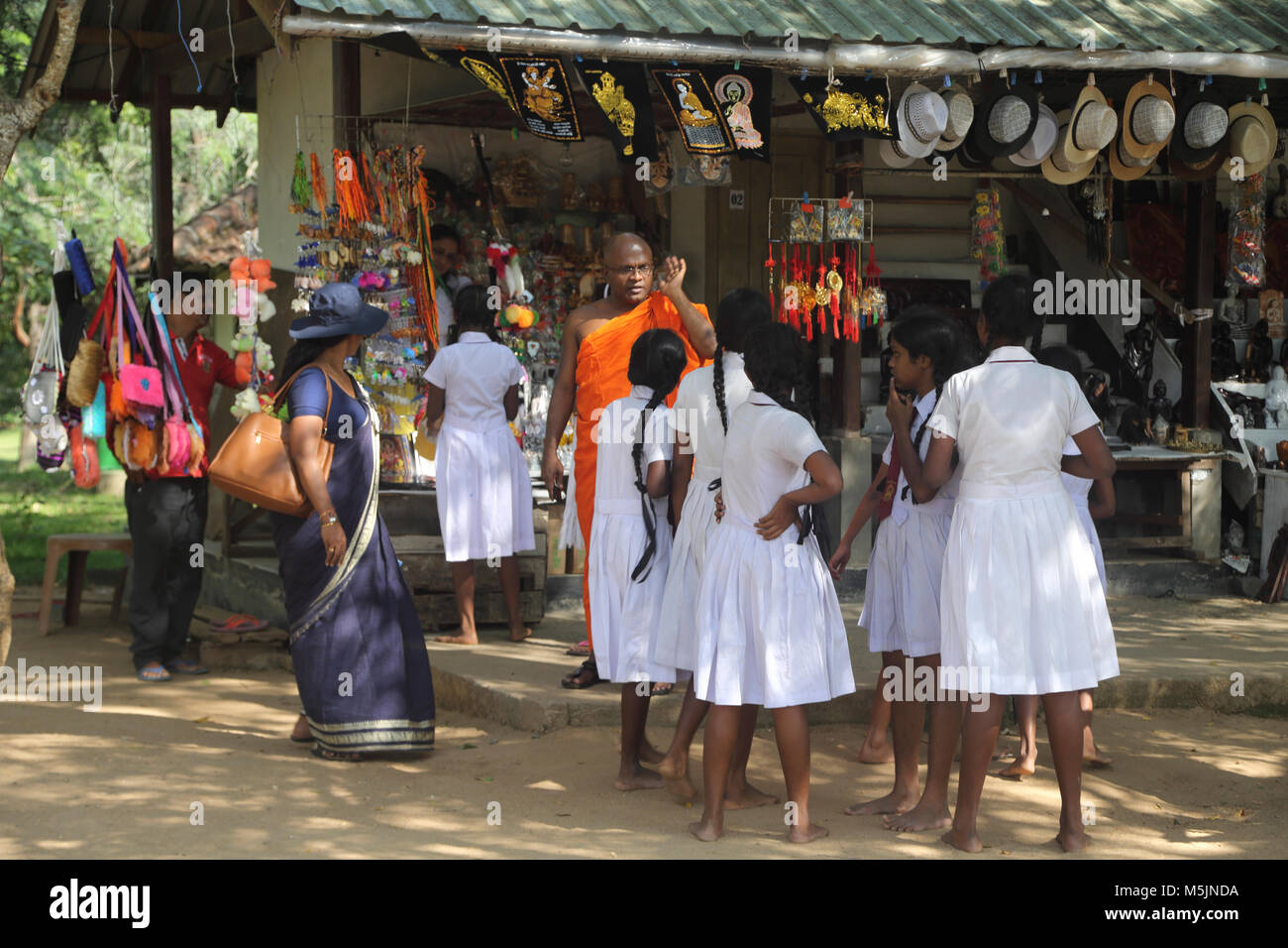 Polonnaruwa North Central Provinz Sri Lanka School Mädchen im Gespräch mit buddhistischen Mönch außerhalb Souvenir Shop Stockfoto