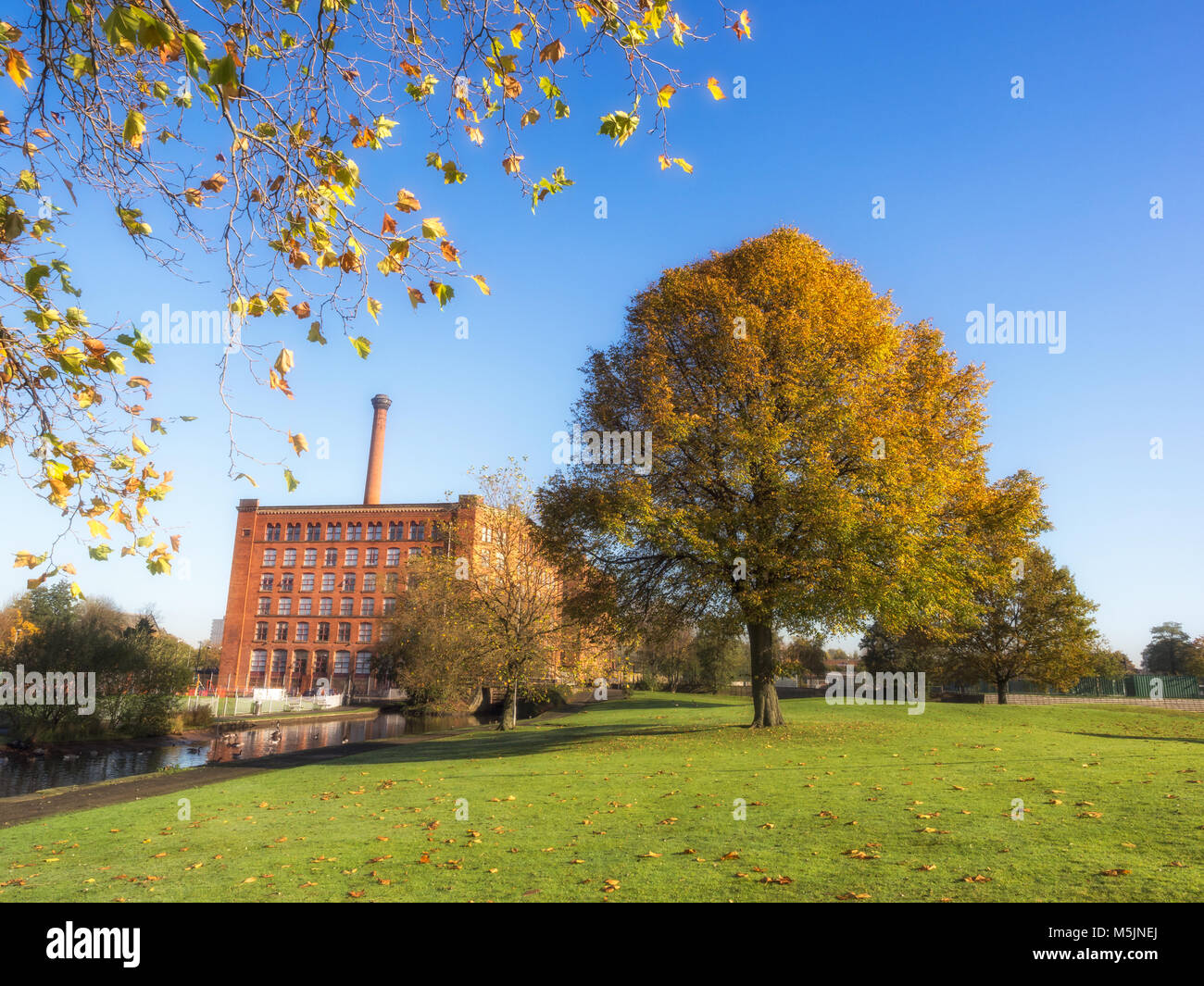 Einem alten englischen Baumwollspinnerei, die neben den Kanal im Herbst mal in Manchester, England Stockfoto