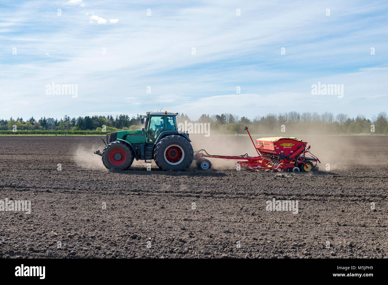 Traktor mit Sämaschine arbeitet ein Feld im Frühling, Län, Dänemark Stockfoto